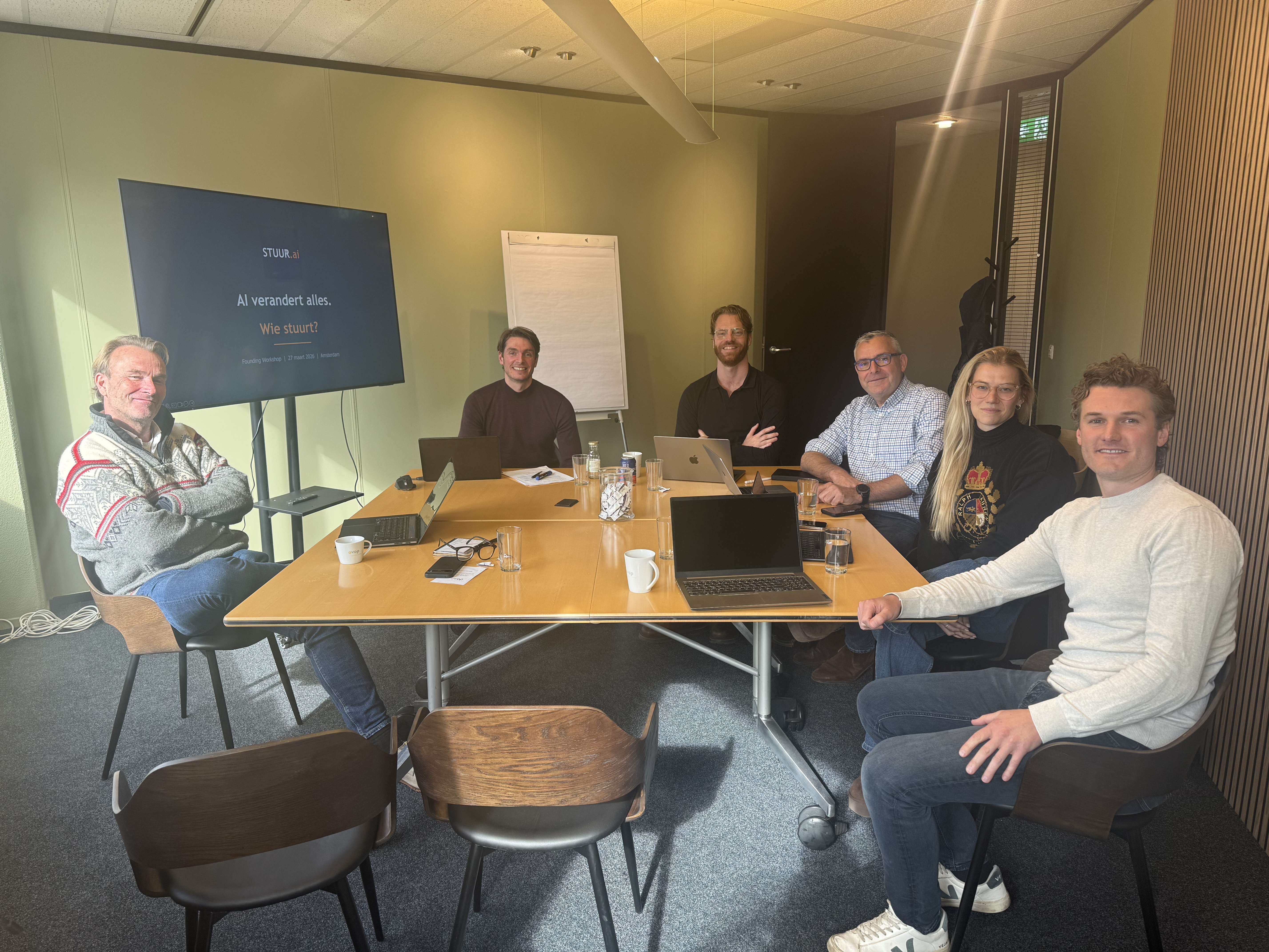 Eerste STUUR.ai Founding Workshop, 27 maart 2026 in Amsterdam. Zes deelnemers aan tafel met laptops, STUUR.ai presentatie op scherm.